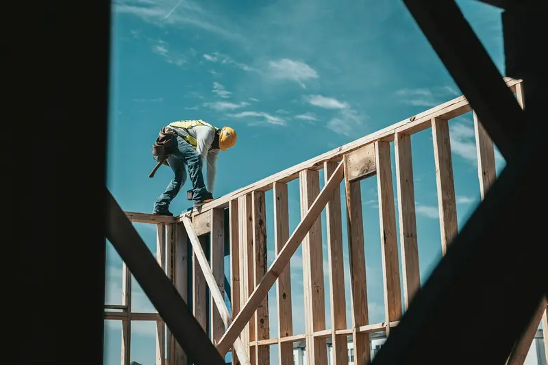 A construction worker in a hard hat on a timber house frame